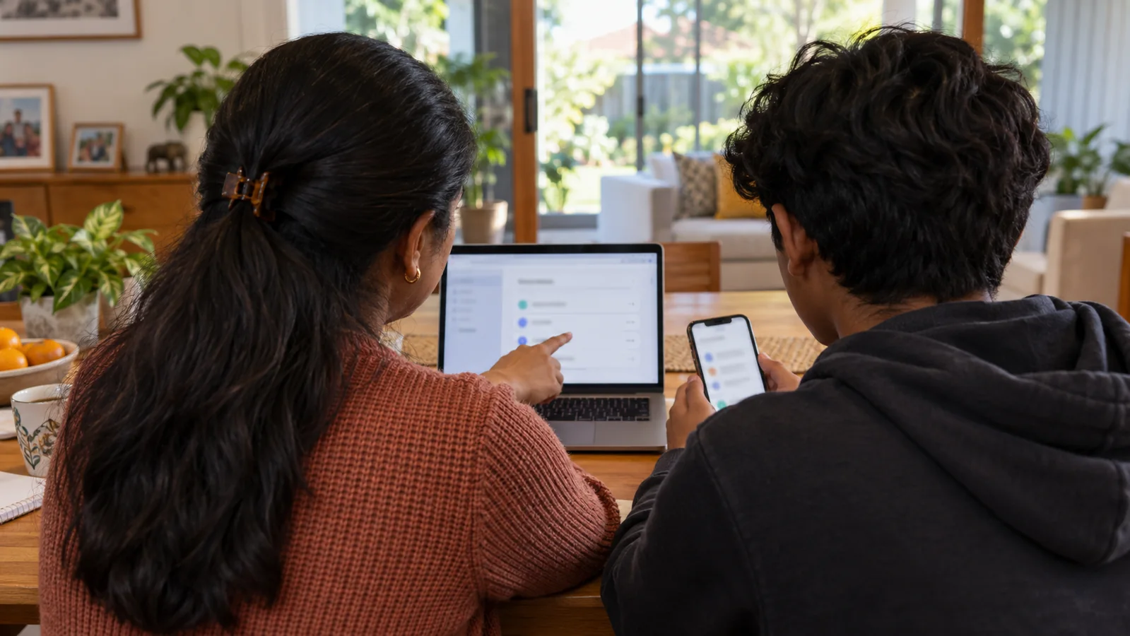 Indian-Australian parent and teenager reviewing online safety settings together at home